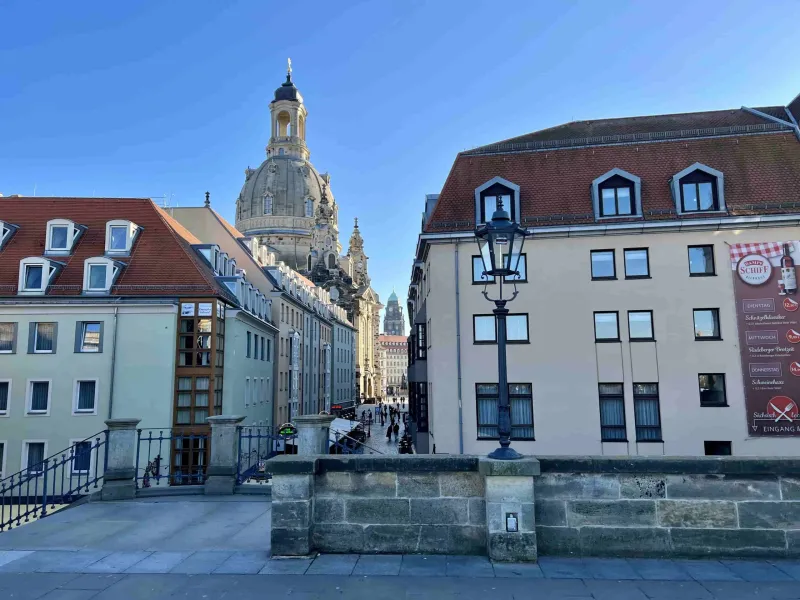 A charming street in Dresden, Germany, with the Frauenkirche dome in the background.