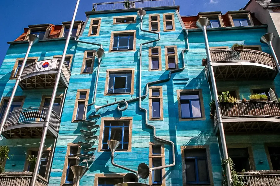 A teal building in Dresden, Germany, with unique musical instrument-shaped downspouts.