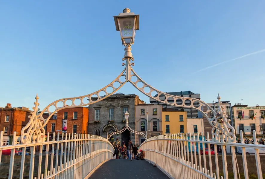 Tourists walking across the beautiful Ha'penny Bridge in Dublin, Ireland.
