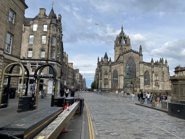Tourists exploring Edinburgh's Old Town, with St. Giles' Cathedral in the background.