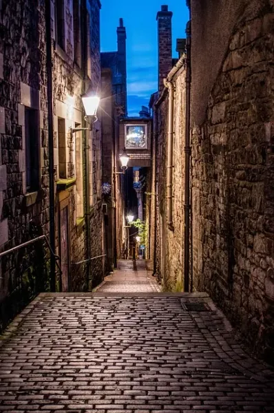 Charming cobblestone alleyway in Edinburgh at night.