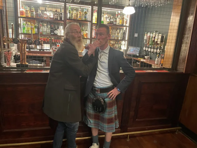 Two men enjoying drinks at a pub in Edinburgh, Scotland.