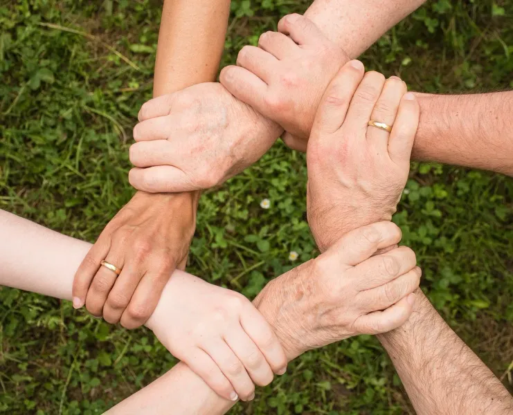 Hands clasped together in a circle, symbolizing unity and teamwork on a group tour in Gdansk.