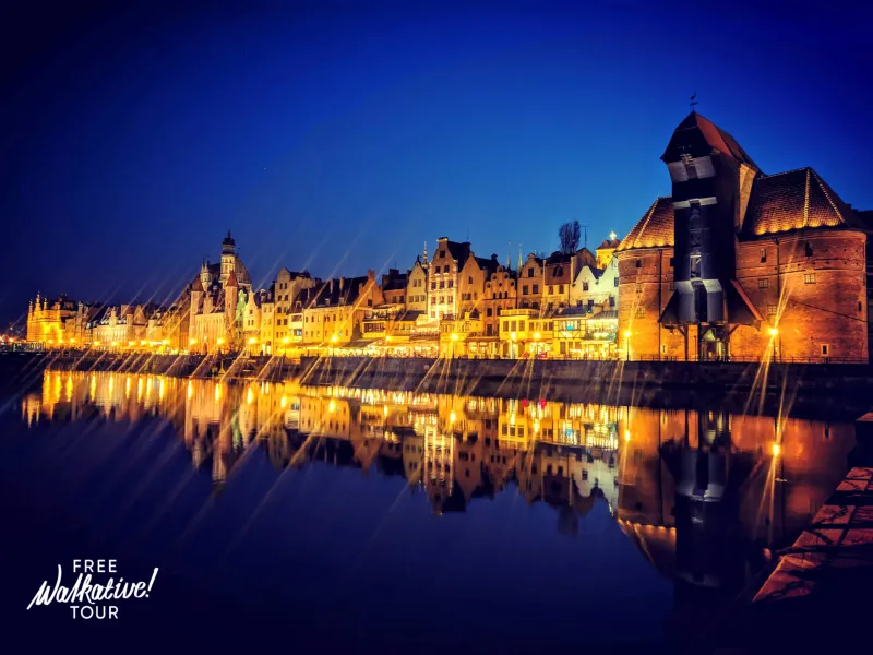 Gdansk's illuminated waterfront at night, reflected in the water. Free Walkative! Tour.
