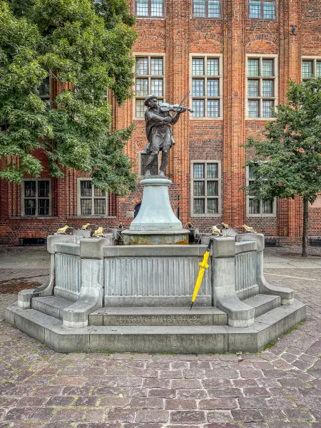 Bronze violinist statue on a fountain in Gdansk's historic square.