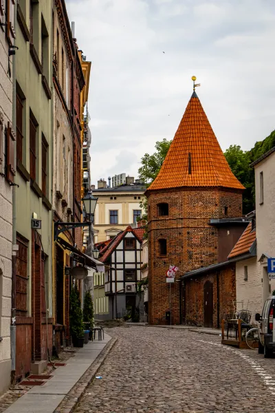 Charming cobblestone street in a historic German city, featuring a brick tower.