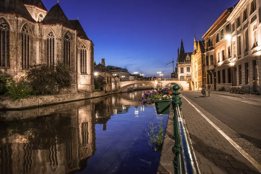 Ghent's charming canal at night, reflecting historic buildings.