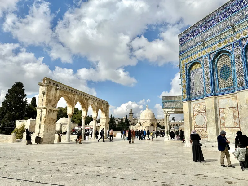 Tourists exploring the Temple Mount in Jerusalem, with the Dome of the Rock visible.