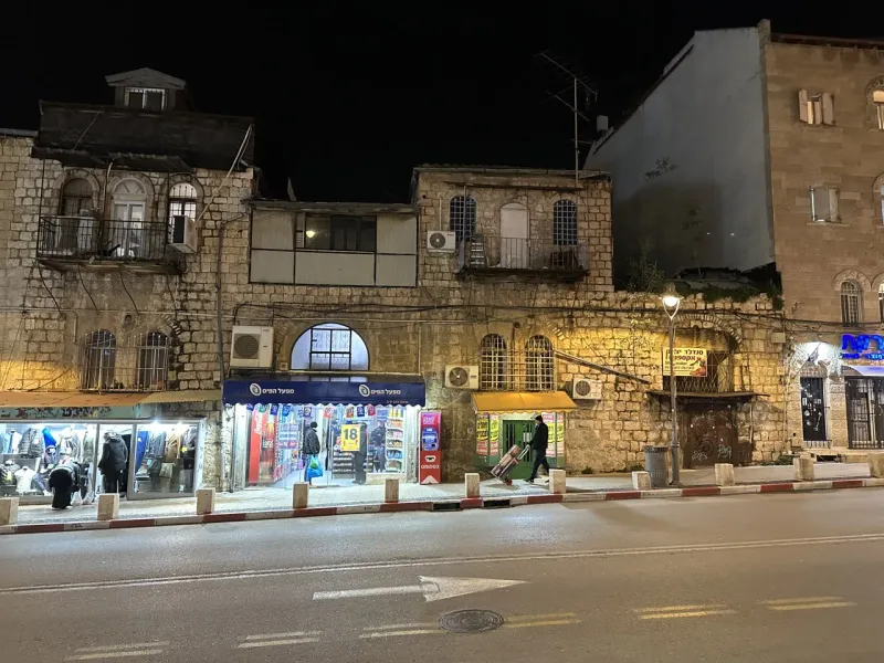 Night scene in Jerusalem's Old City, showing historic stone buildings and a quiet street.