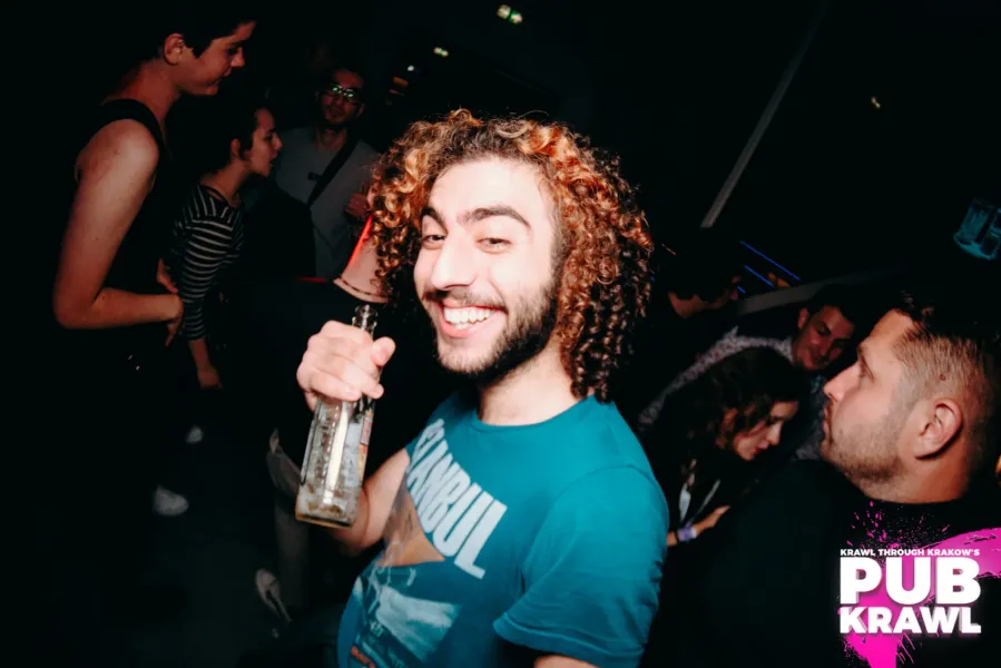 A smiling man enjoys a pub crawl in Krakow, Poland.