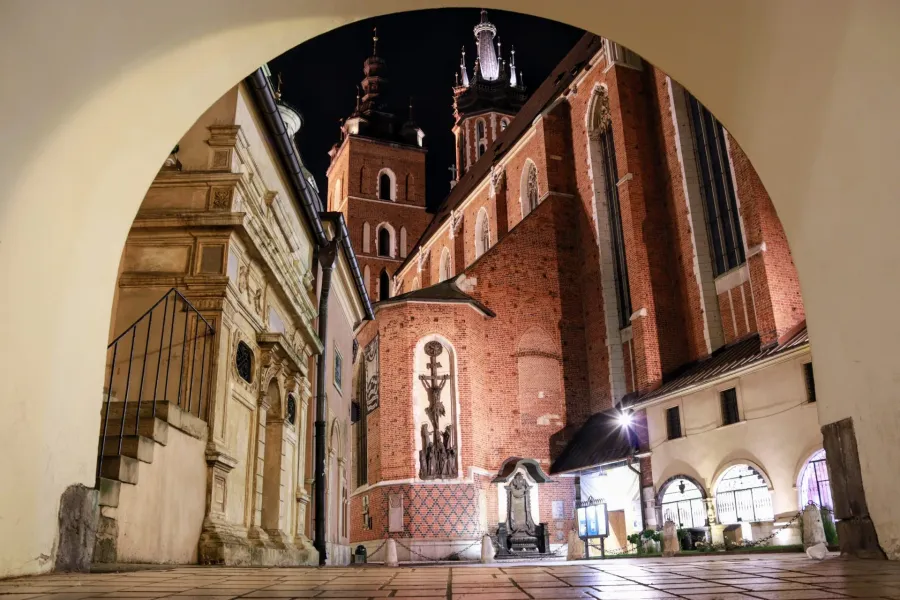 St. Mary's Basilica in Krakow at night, viewed through an archway.