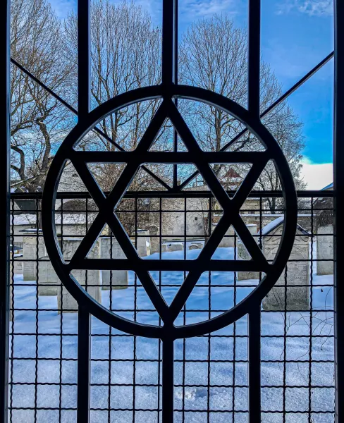 Star of David gate overlooking a snow-covered Jewish cemetery in Krakow, Poland.