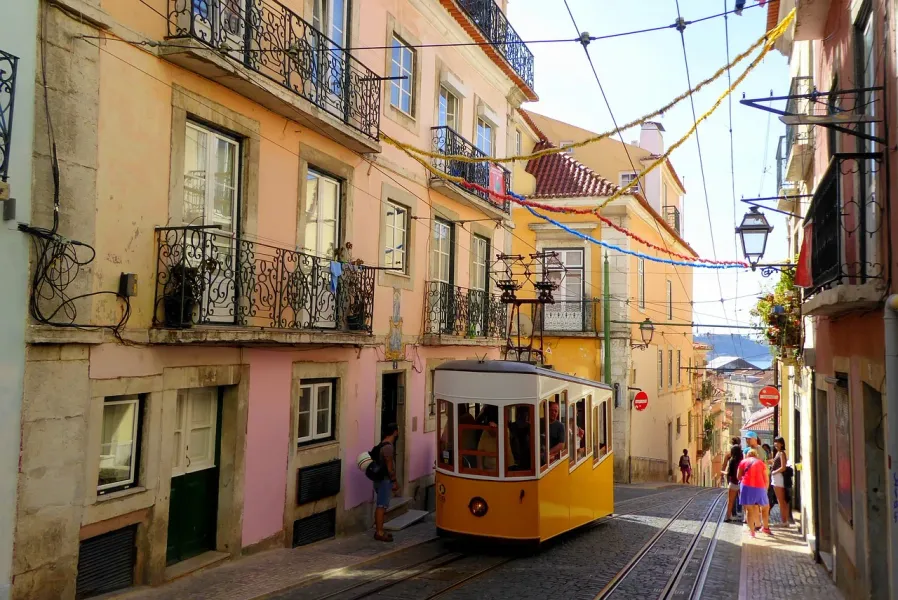 A yellow tram climbs a hill in Lisbon's Alfama & Mouraria districts.