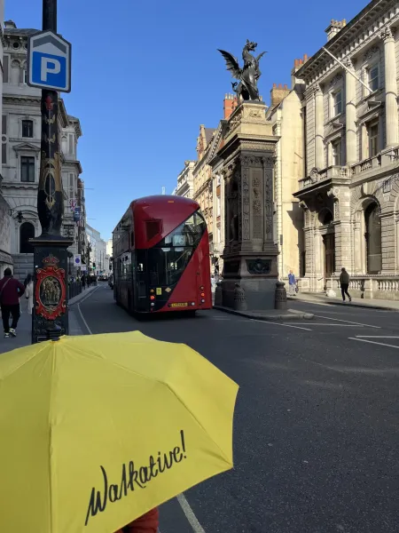 A yellow umbrella with 'Walkative!' on a London street.