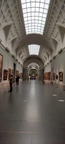 Grand hallway in an art museum with paintings and visitors.