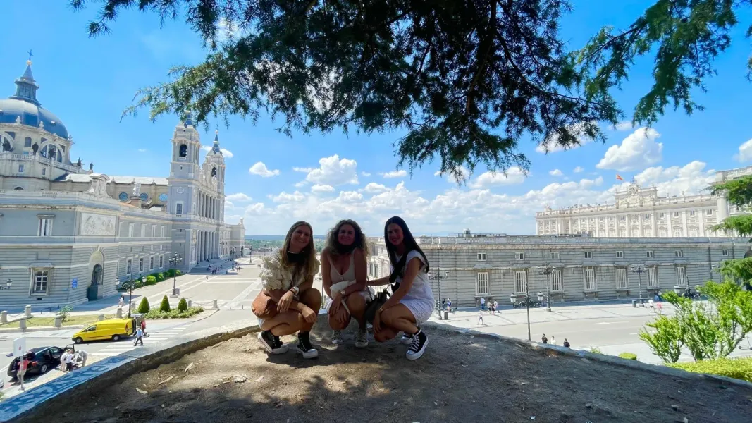 Three friends enjoying a city break in Madrid, with the Almudena Cathedral and Royal Palace in the background.