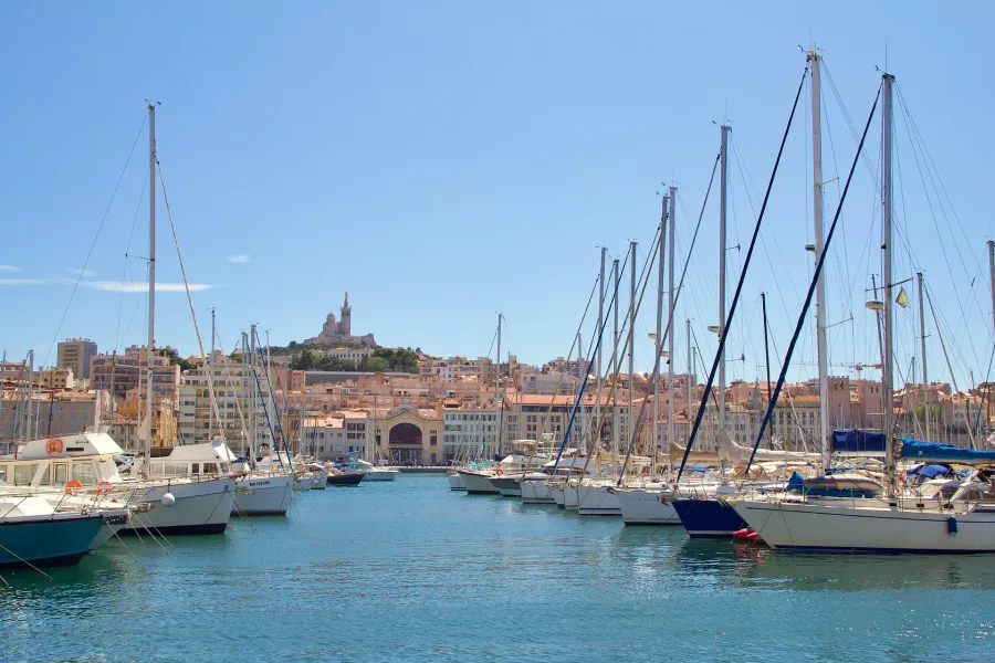 Marseille harbor with sailboats and Notre-Dame de la Garde in the background.
