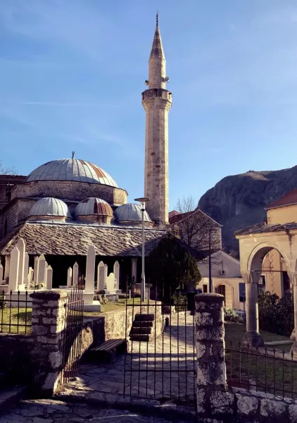 A serene mosque in Montenegro with a tall minaret and a peaceful graveyard.