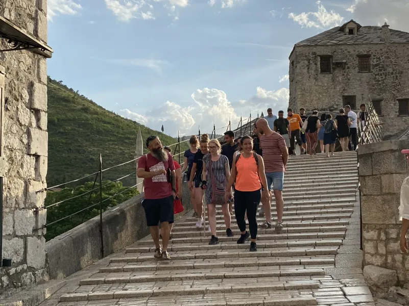 Guided tour group walking across the historic Stari Most bridge in Mostar.