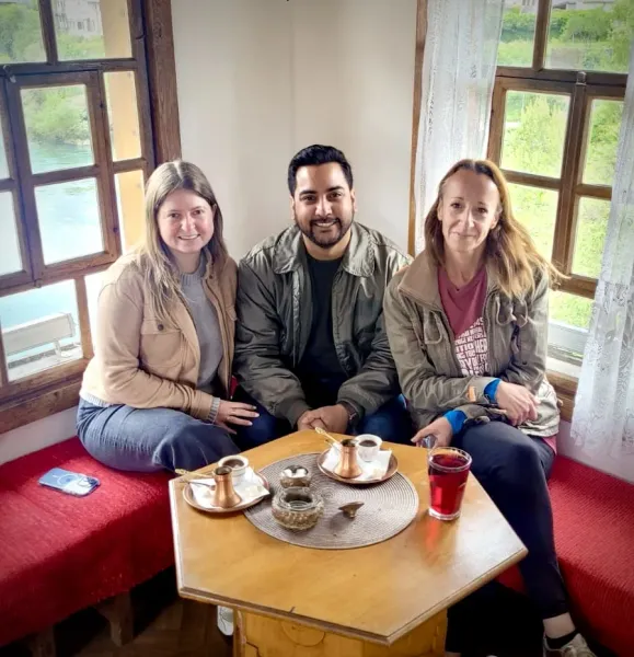 Three tourists enjoy traditional coffee with a river view in Mostar.