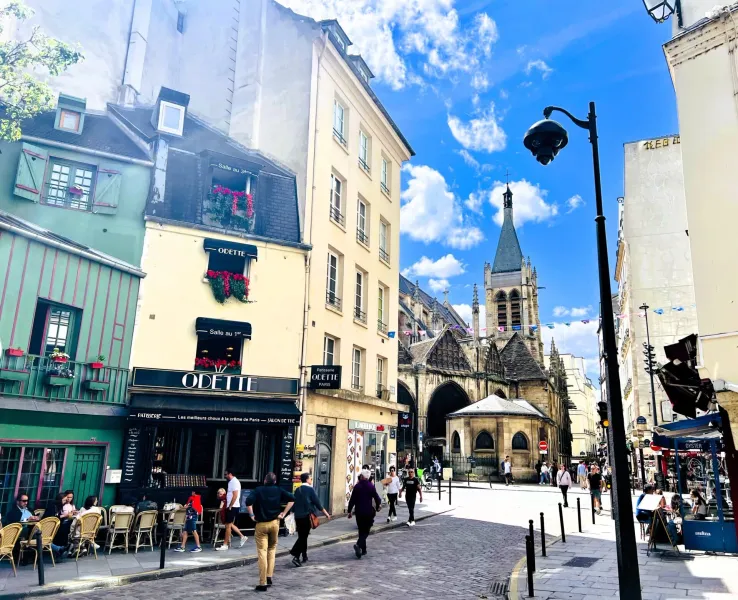 Sunny Parisian street scene with a charming cafe and historic church.