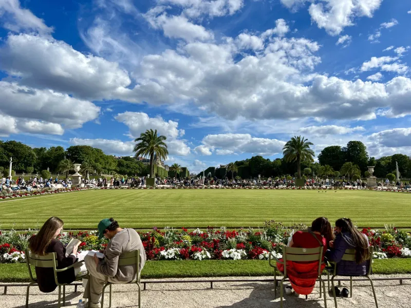 Tourists relax in a beautiful Parisian garden.
