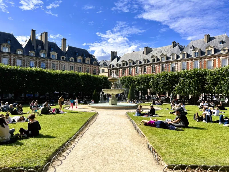 People relaxing in a sunny Parisian square.