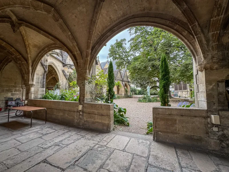 Serene courtyard in Paris, seen through ancient stone arches.
