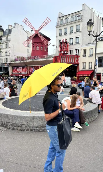 A tour guide in Paris points towards the Moulin Rouge.