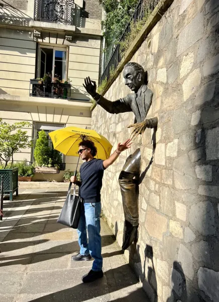 A tour guide in Paris interacts with a unique bronze sculpture.