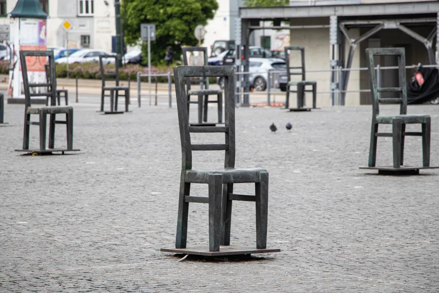 Empty bronze chairs arranged in a plaza, a poignant memorial.