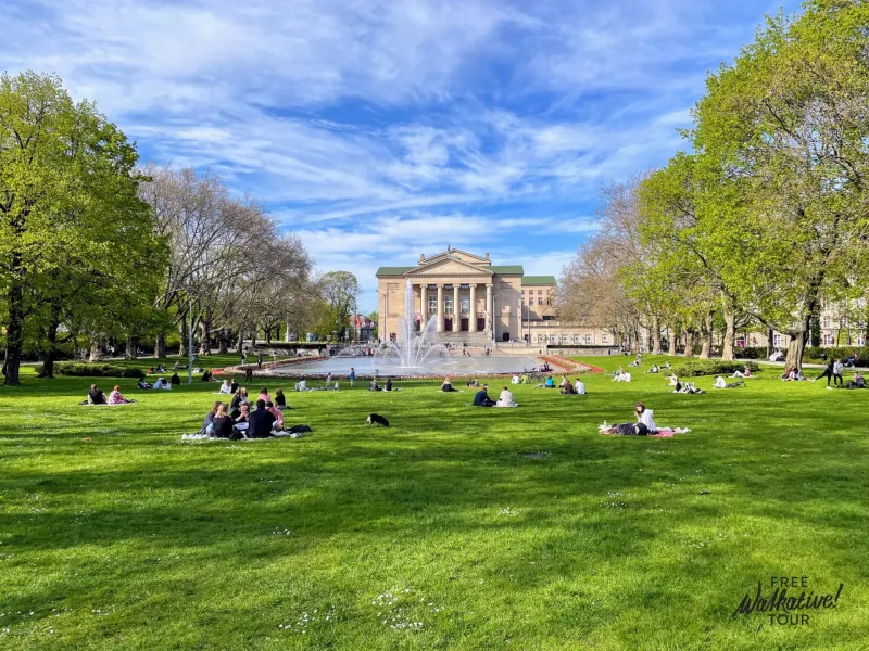 Relaxing scene in Poznań's park with the Grand Theatre in the background.