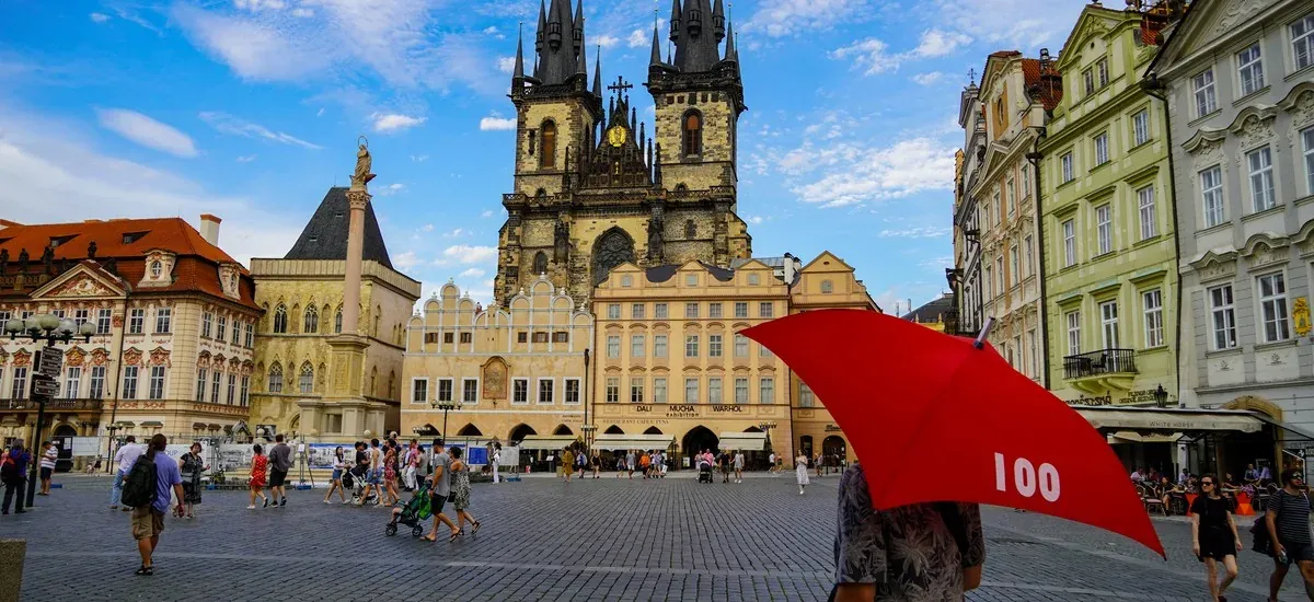 Tourists exploring Prague's Old Town Square, with the Church of Our Lady before Týn in the background.