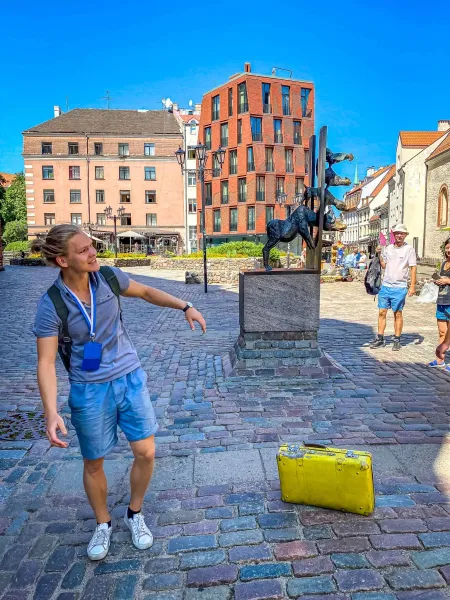 A tour guide in Riga, Latvia, points to a unique bronze sculpture in a cobblestone square.