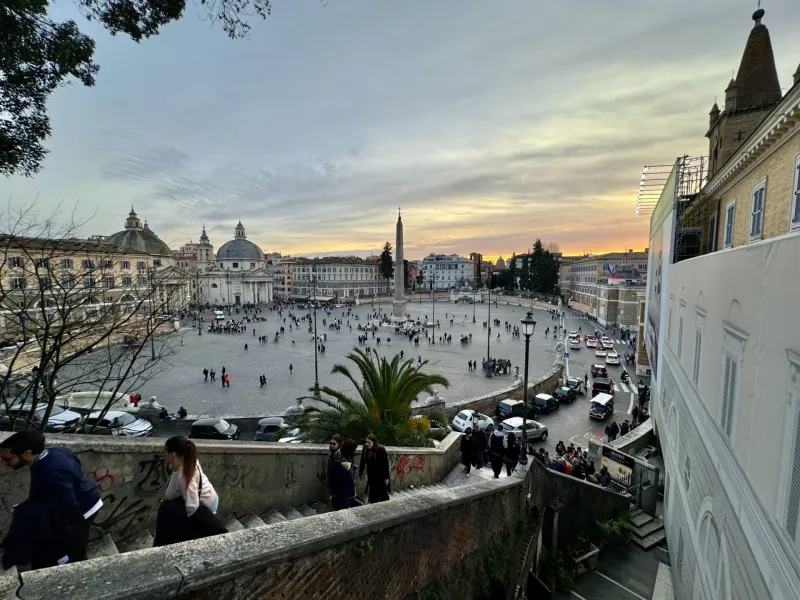Tourists enjoying a sunset view of Piazza del Popolo in Rome, Italy.