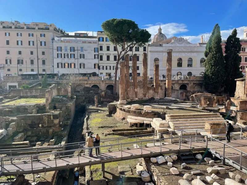 Tourists exploring the ancient ruins of Largo Argentina in Rome.