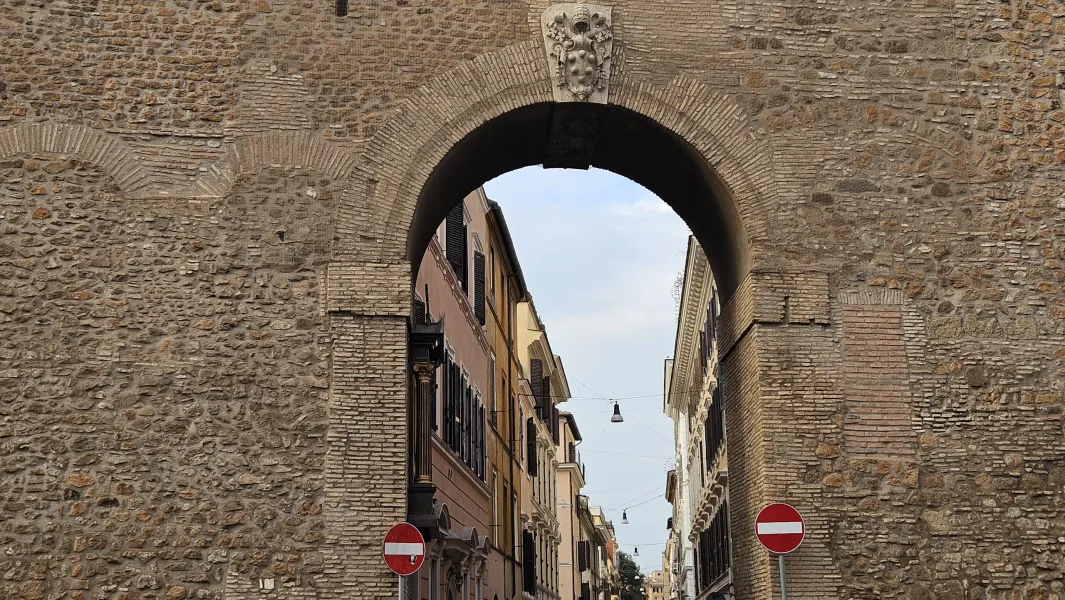 Ancient Roman archway in Rome, offering a glimpse of a charming street.