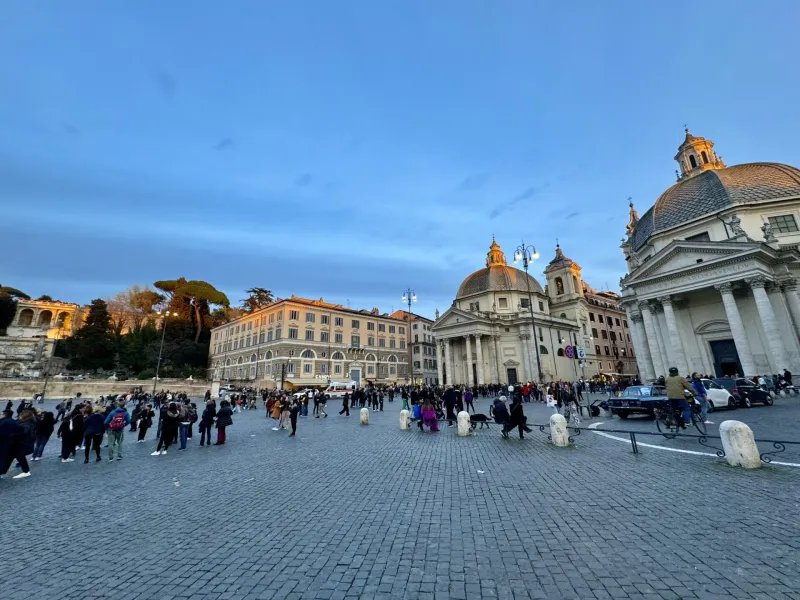 Tourists gather in Rome's Piazza del Popolo at sunset.