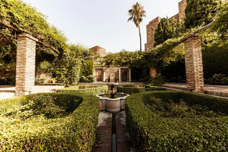 Serene courtyard in Seville, Spain, featuring a fountain and lush greenery.