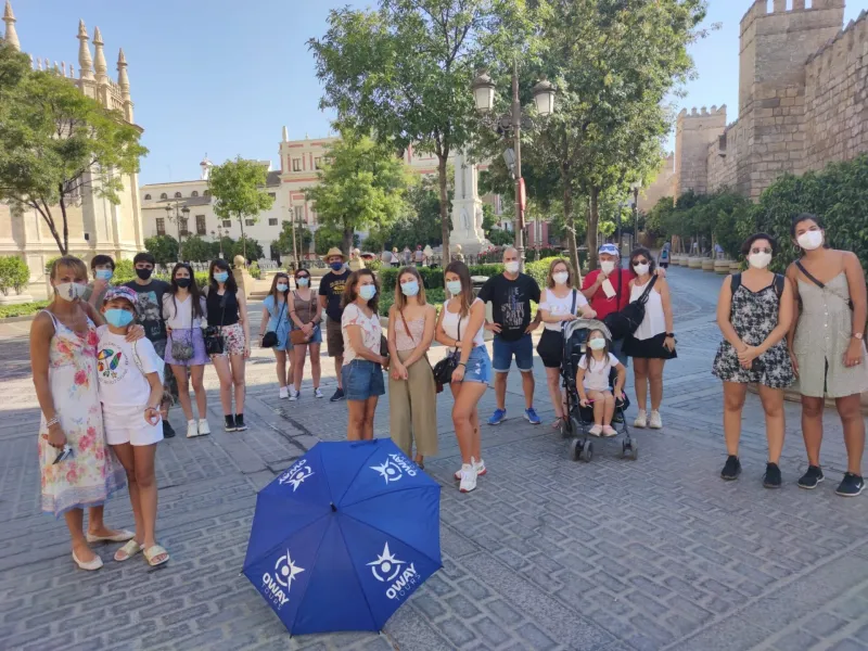 A guided tour group in Seville, Spain, poses for a photo near historic city walls.