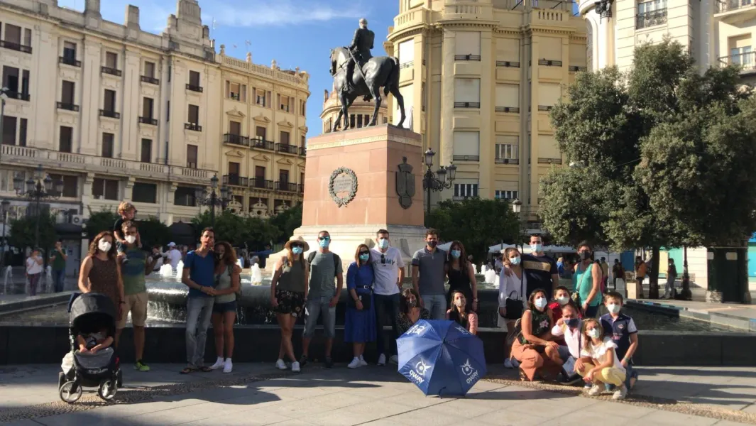 A tour group in Seville, Spain, poses in front of an equestrian statue.