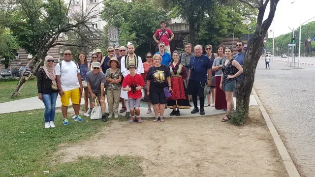A diverse tour group smiles for a photo in Sofia, Bulgaria, near a historical monument.