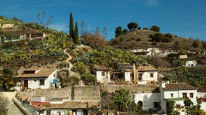 Charming hillside town in Spain with whitewashed houses and lush vegetation.