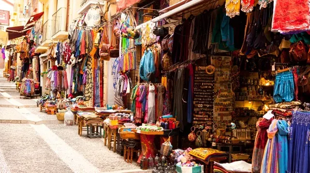 Colorful street market in Spain, filled with textiles and souvenirs.