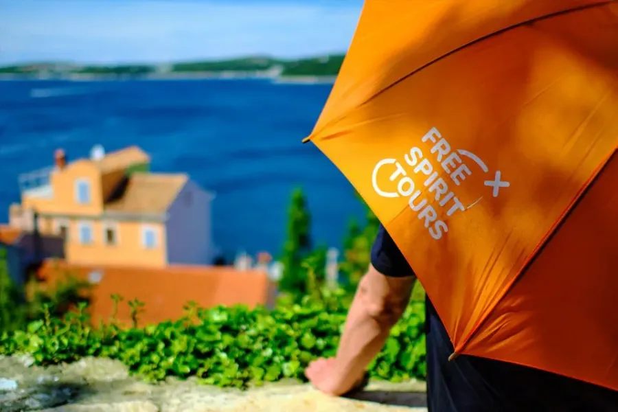 A Free Spirit Tours guide with an orange umbrella, enjoying a scenic view of Split, Croatia.