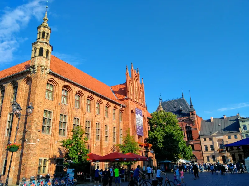 Tourists exploring the Old Town Hall in Toruń, Poland.