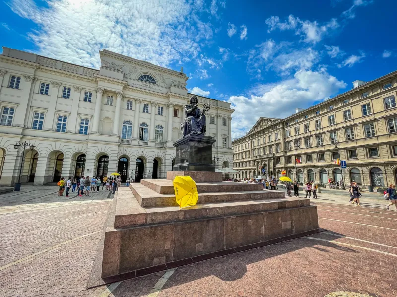 Tourists explore the Copernicus Monument in Warsaw's Old Town.