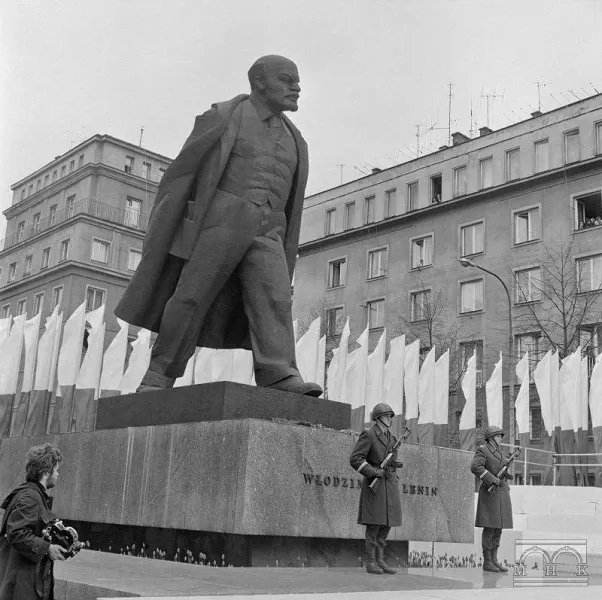 A large statue of Lenin in Warsaw, Poland, guarded by soldiers.