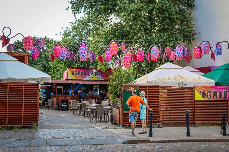 Tourists enjoying the vibrant atmosphere of Ogród Żabkowski in Warsaw, Poland.