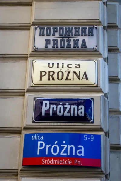 Four street signs on a building in Warsaw, Poland, all indicating Próżna Street.